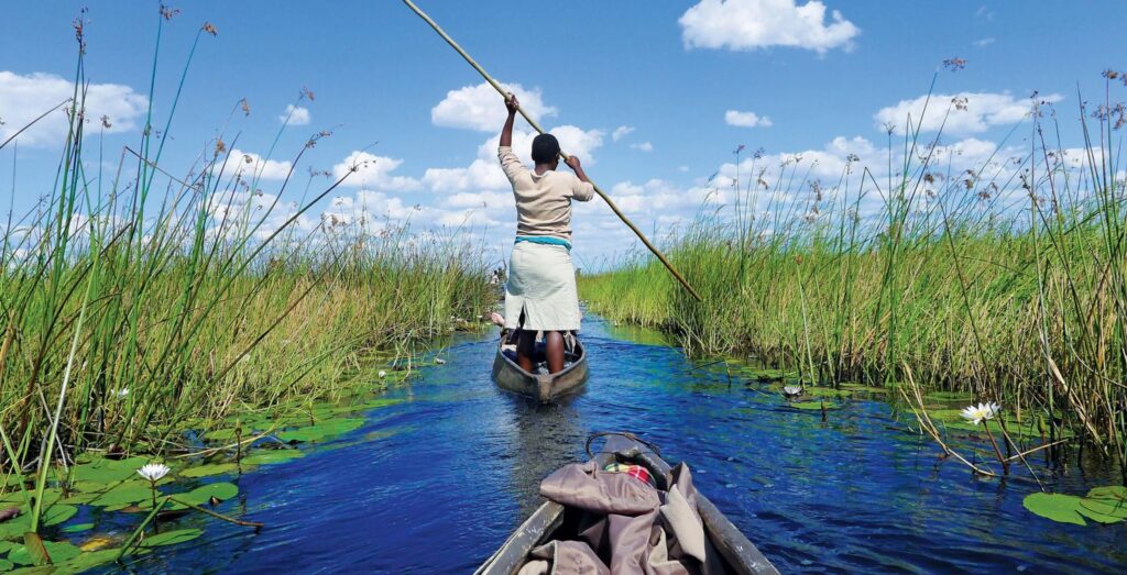 Une poling-woman guide son mokoro à la perche à travers les méandres du Delta de l'Okavango.