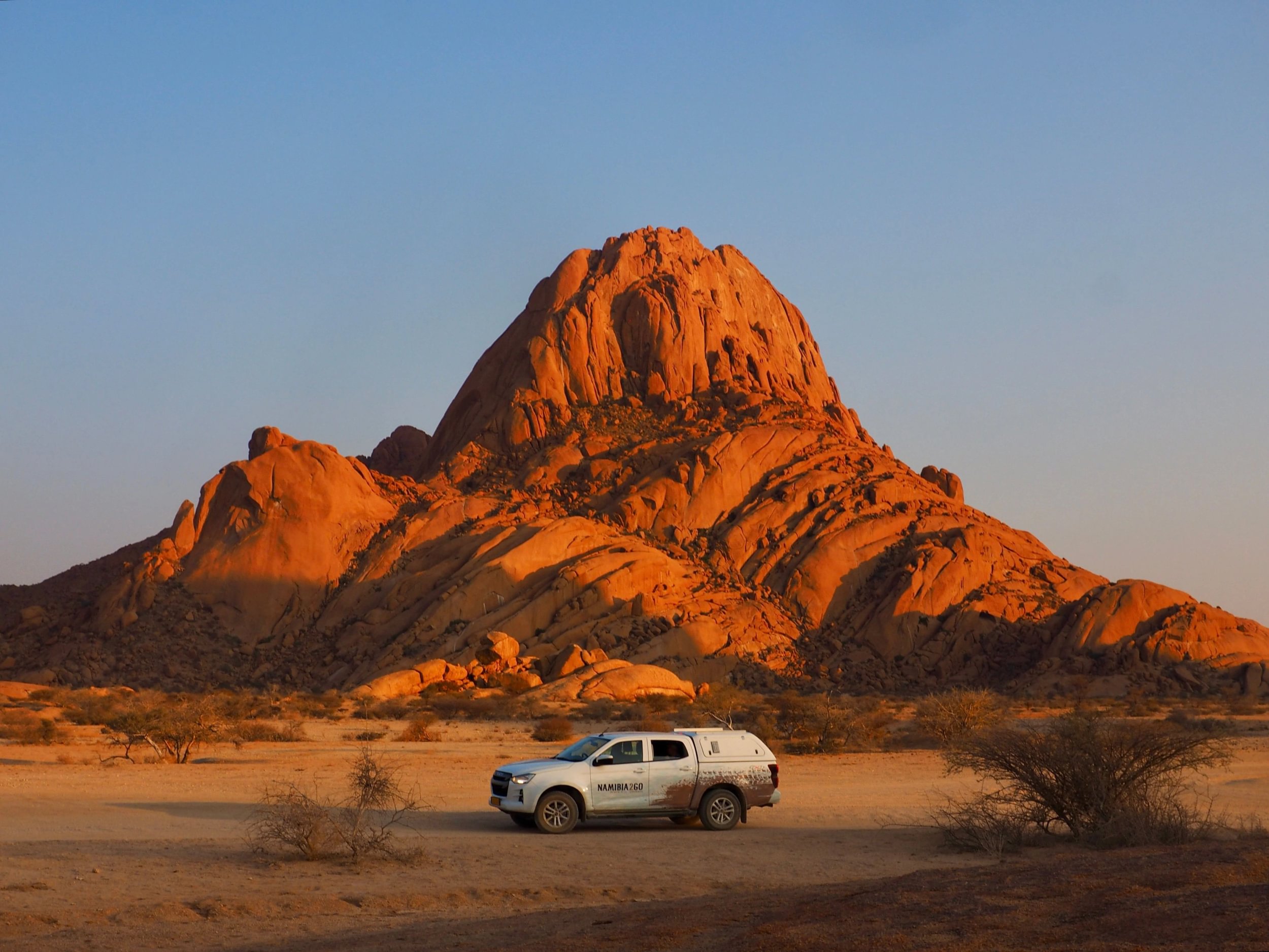 Véhicule de safari stationné au pied de Spitzkoppe au coucher du soleil